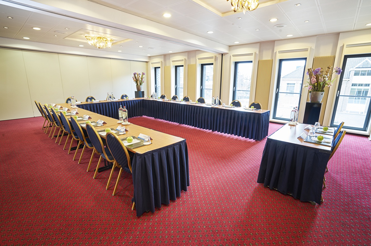 Vergaderzaal Marie Louise in Amrâth Grand Hotel de l’Empereur met rood tapijt, daglicht en opstelling voor een zakelijke bijeenkomst.