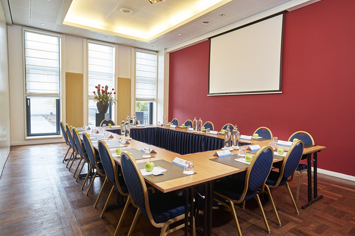 Vergaderzaal Josephine in Amrâth Grand Hotel de l’Empereur met U-opstelling, rode accentmuur en daglicht via hoge ramen.