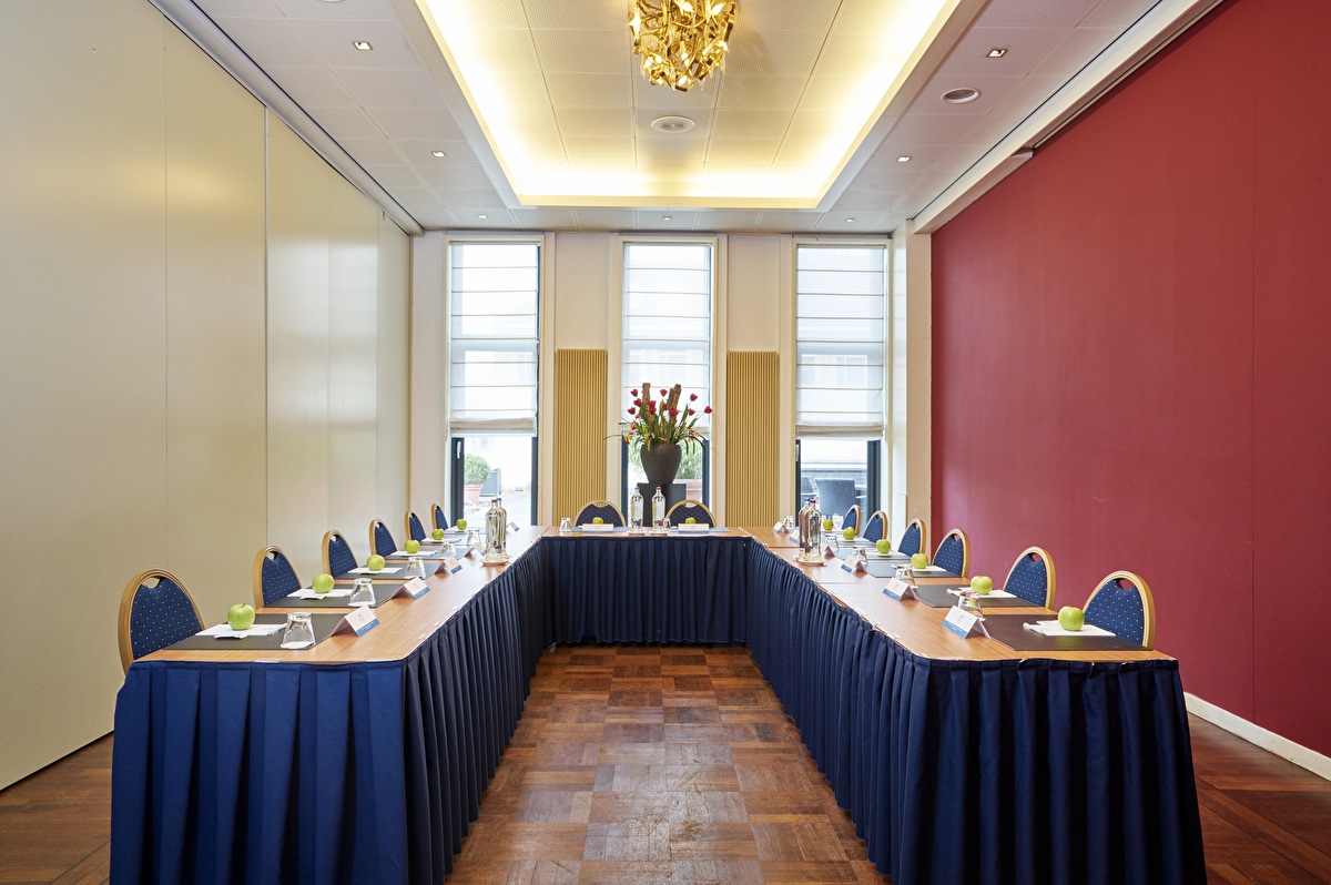 Vergaderzaal Josephine in Amrâth Grand Hotel de l’Empereur met U-opstelling, kroonluchter en drie hoge ramen.